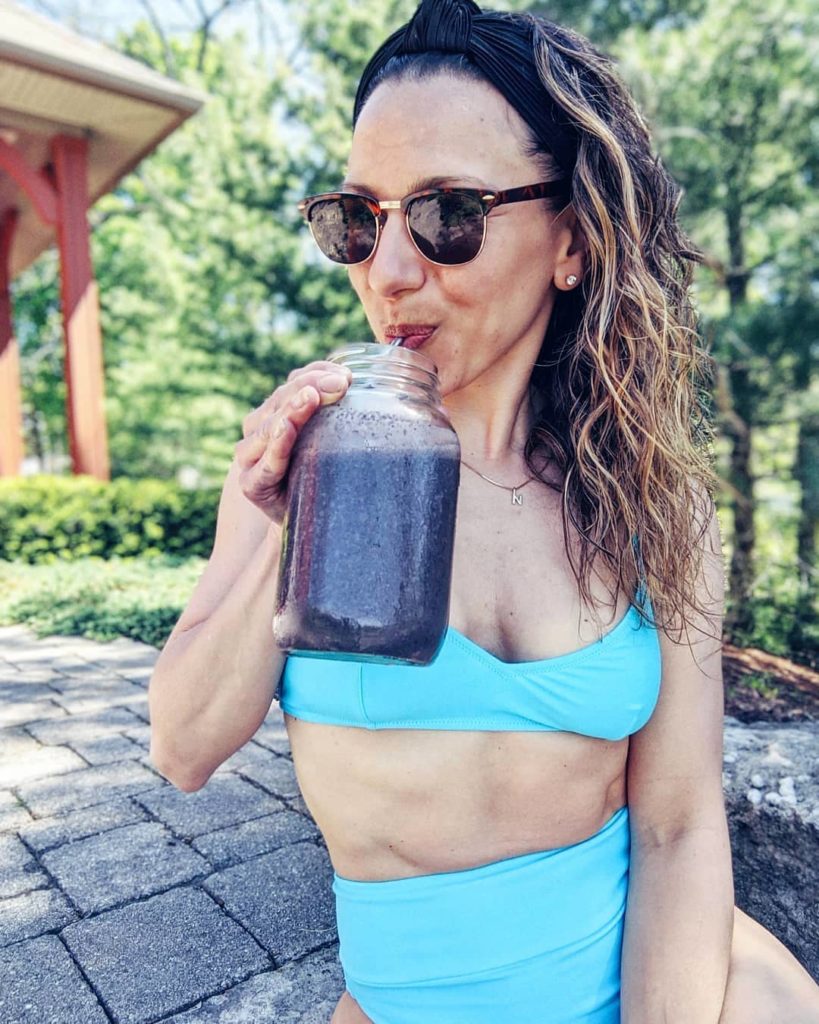 Natalie Pupo drinking a smoothie outside in a bikini